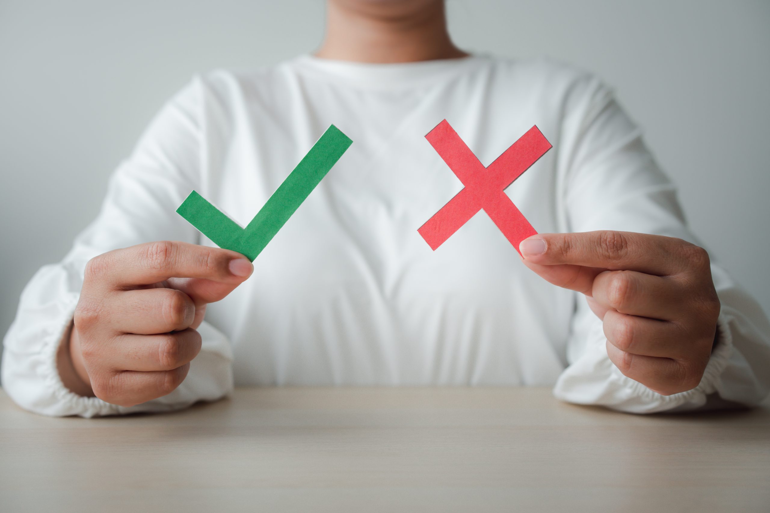 Woman with tick and cross concept of differentiation and opposite side. Green tick to accept, agree but red cross for disagree or denied. Business trend concept using wooden blocks.