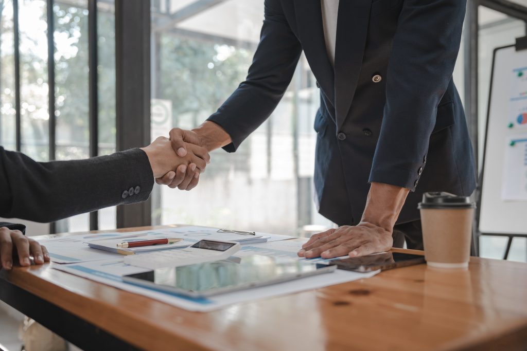 Shaking hands of businessman and Certified Public Accountant (CPA) auditor providing accounting and auditing services in the same company and stock market chart data and anti bribery of accounting