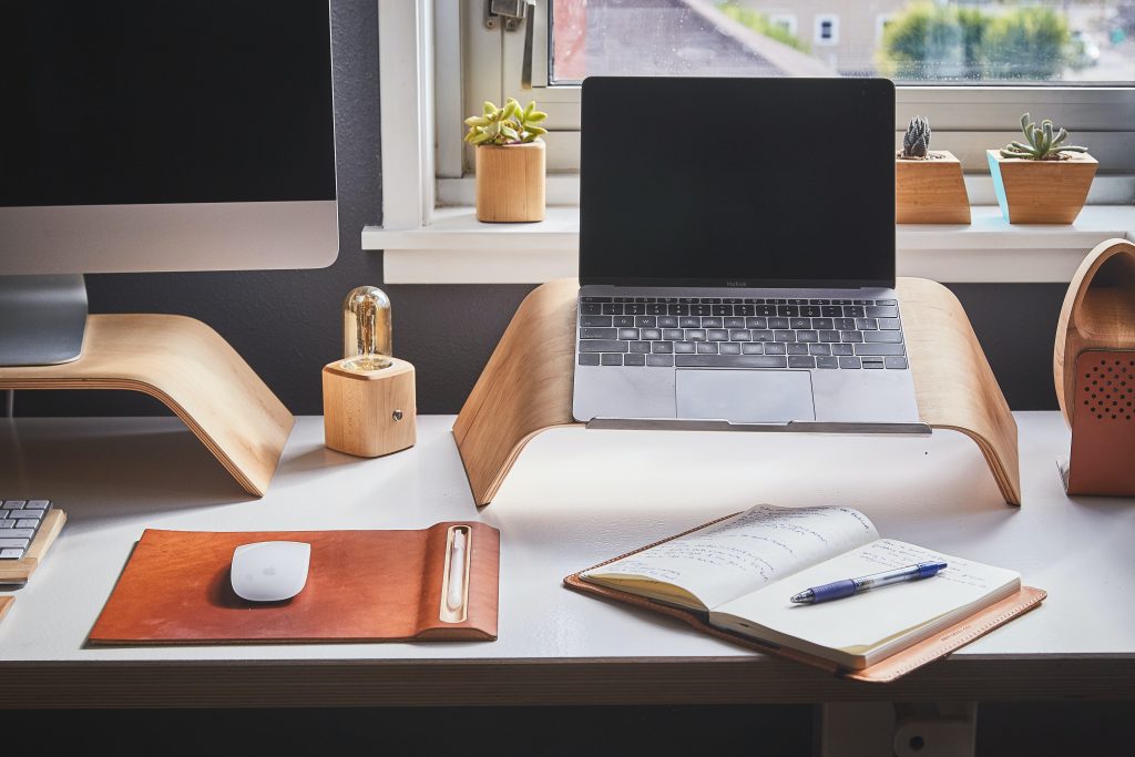 notebook with a ballpen on top of it with a laptop on the back