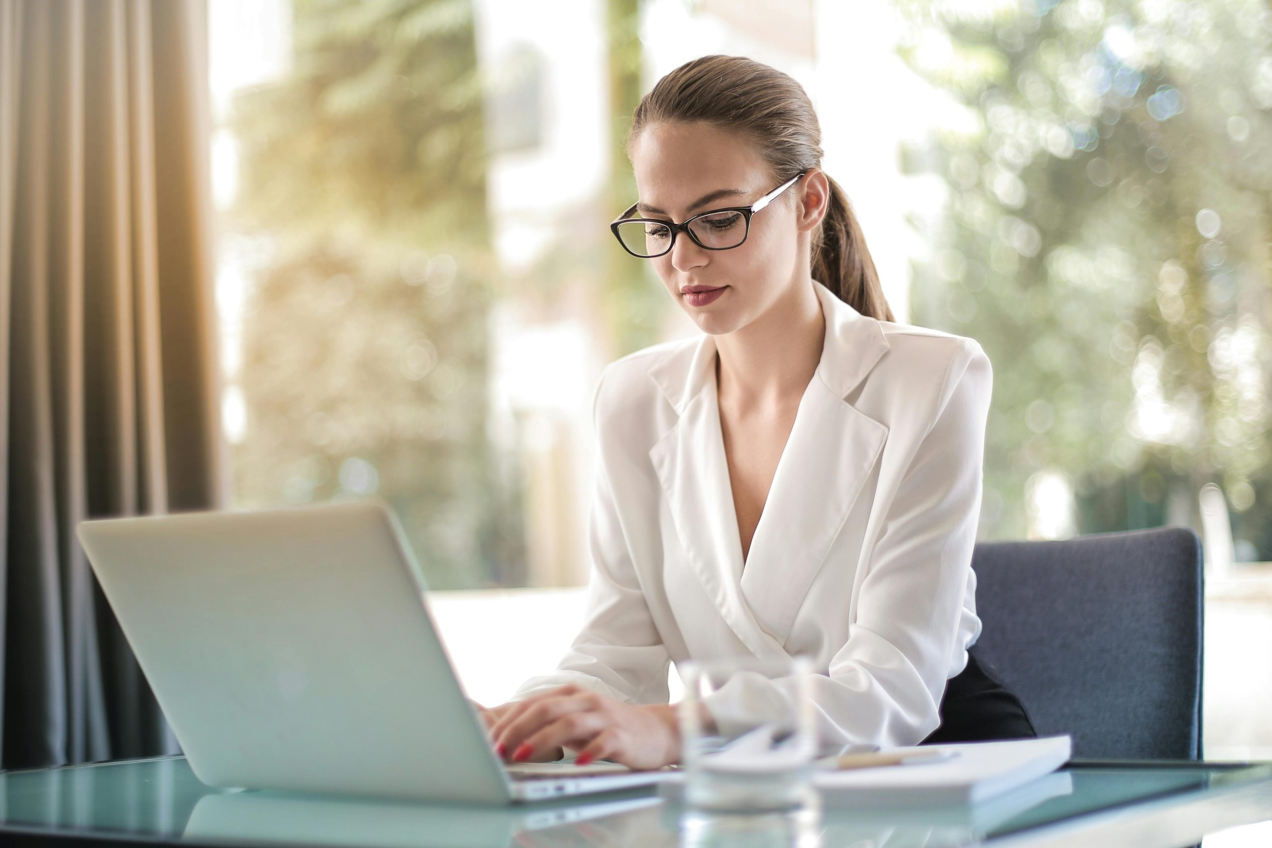 female accountant wearing white blouse using a laptop