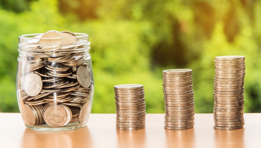 stack of coins beside a glass that is full of coins