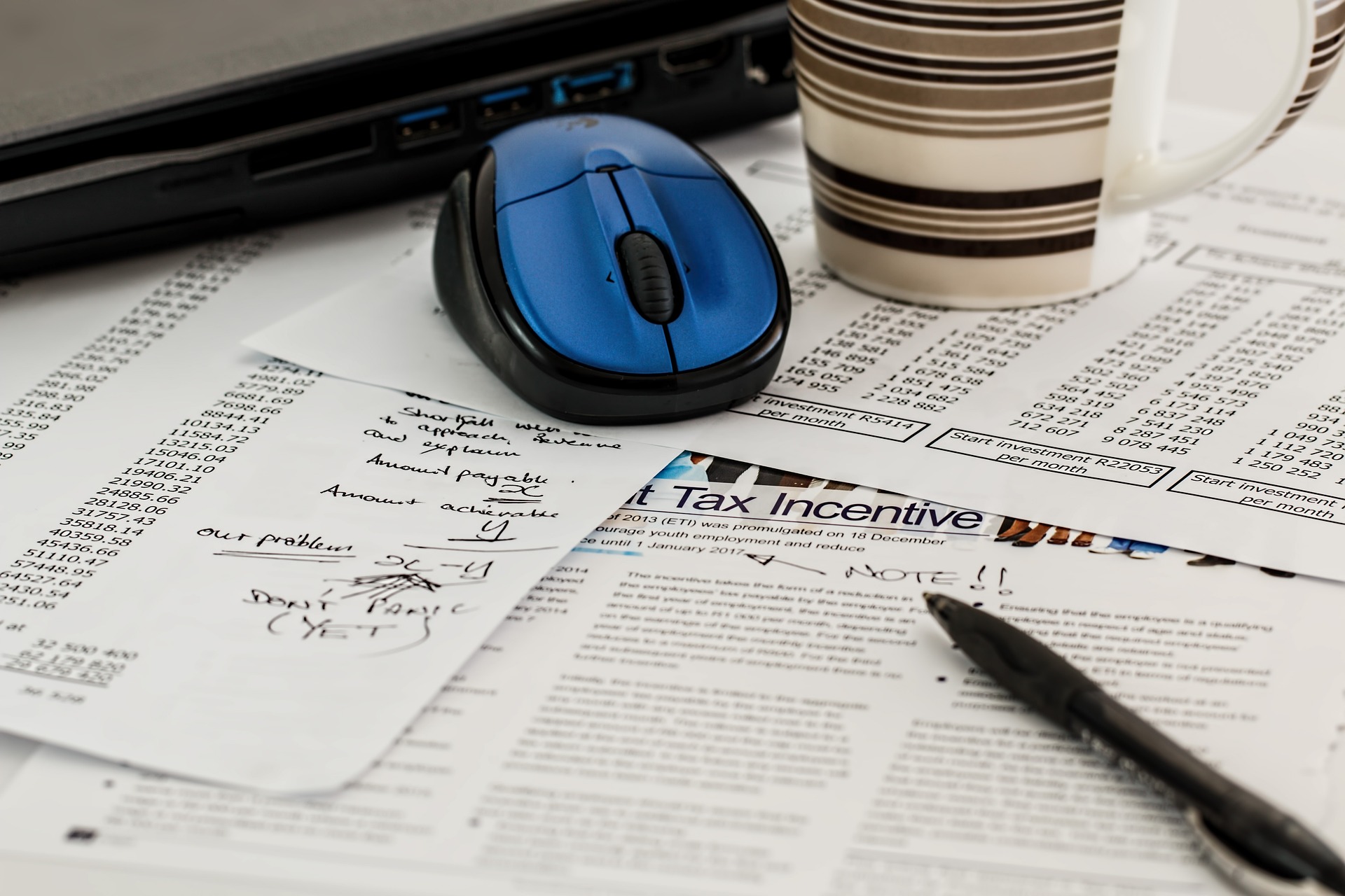 blue mouse cup and a pen above the papers